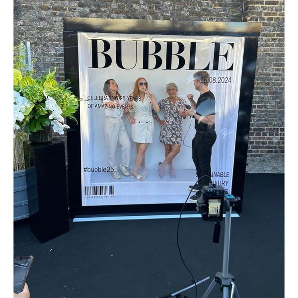 3 female, 1 male guest standing inside a Magazine photo box 