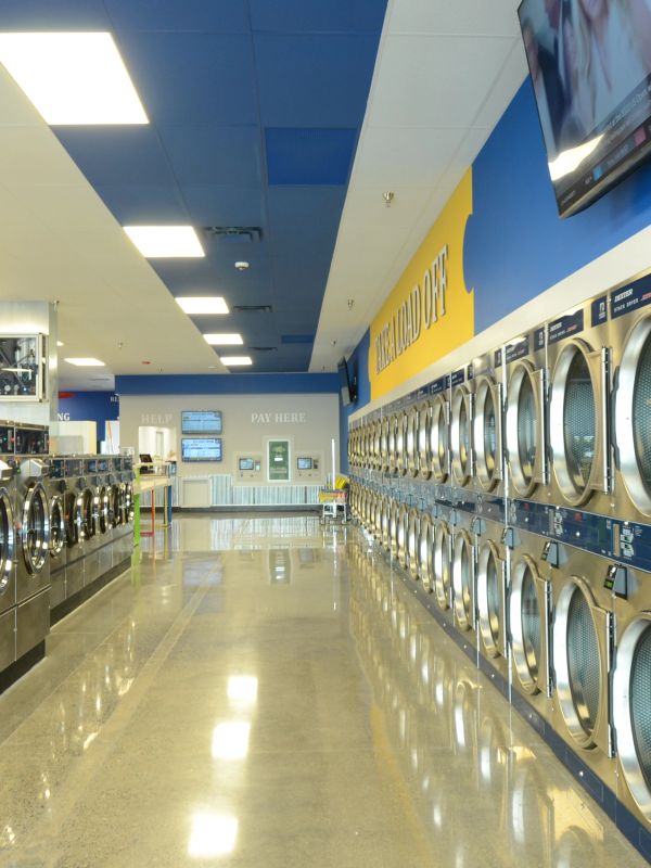 Interior of a modern laundromat with rows of washers and dryers.