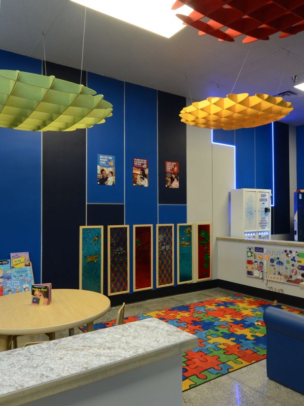 Colorful playroom corner with puzzle carpet, books, and vending machines.