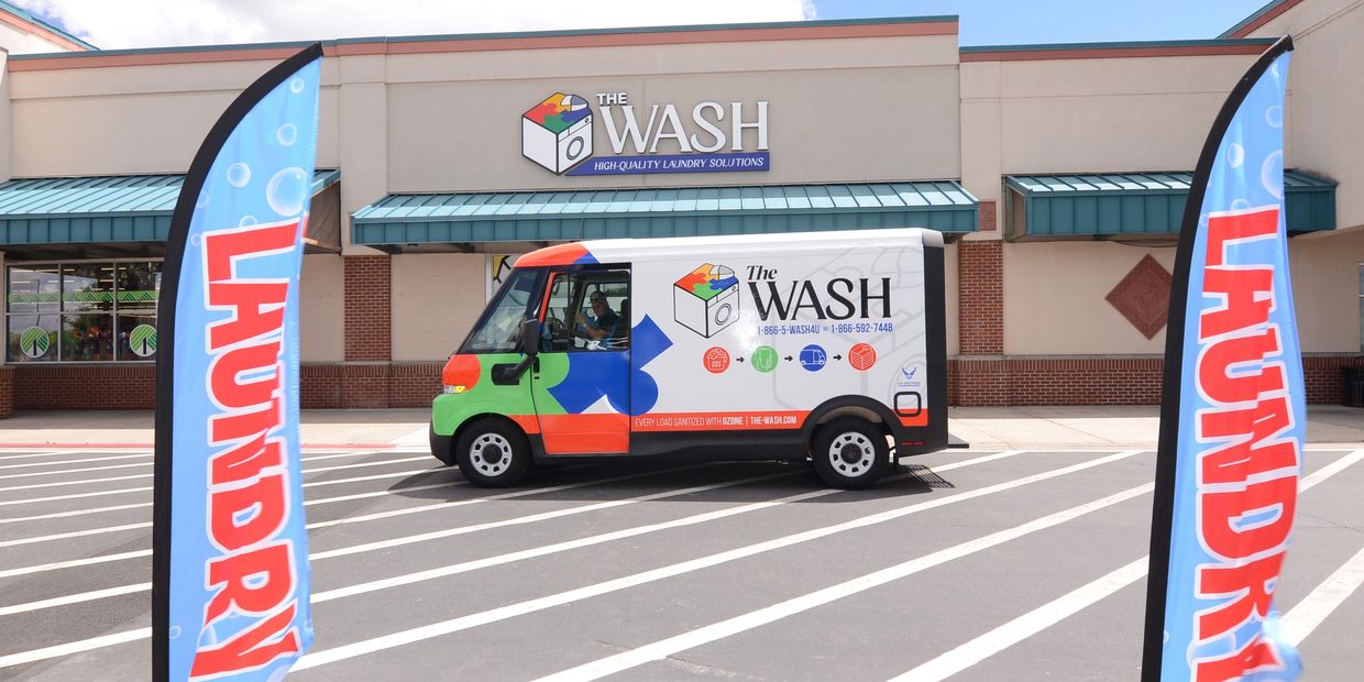Colorful laundry service van parked outside The Wash store with laundry banners.