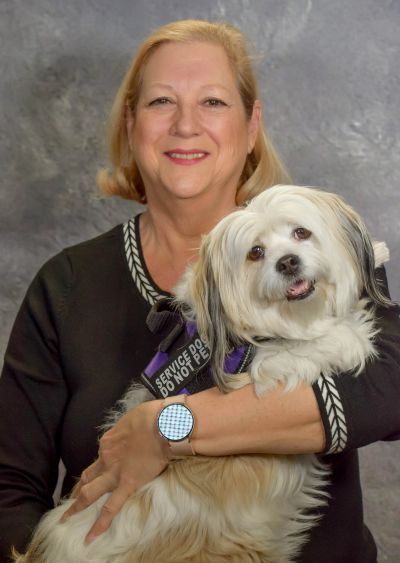 Woman holding a service dog.