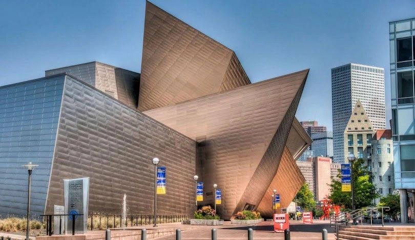 Modern architectural structure with sharp, angular metallic surfaces in an urban setting.