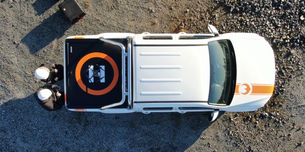 A white vehicle with orange stripes viewed from above on rocky ground.