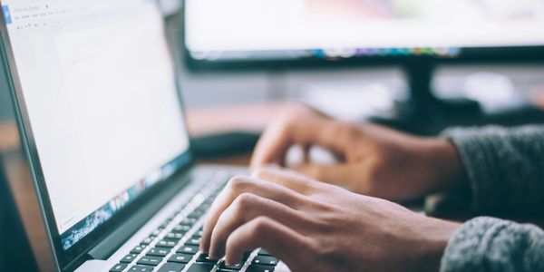 Person typing on a laptop with a document open on screen.