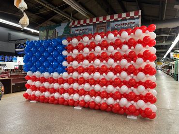 A large American flag made from red, white, and blue balloons.