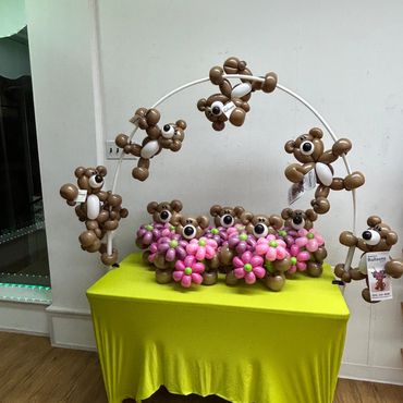 Balloon animals shaped like bears arranged on and around a bright yellow table.