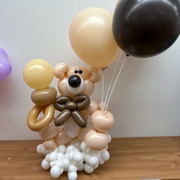 A balloon sculpture of a cute dog holding balloons.