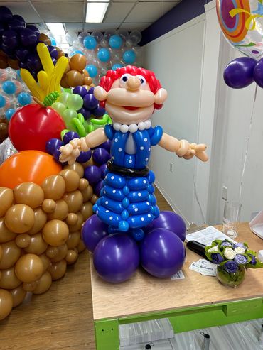 Colorful balloon sculpture of a cartoon character with red hair and blue outfit.