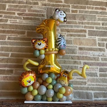Colorful jungle-themed balloon decoration with a large gold number one and animal faces.