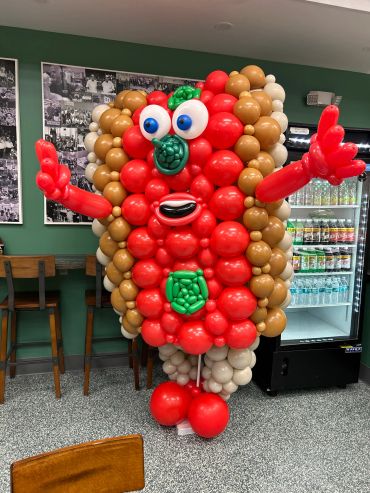 A colorful balloon sculpture of a sandwich character with expressive eyes and arms.