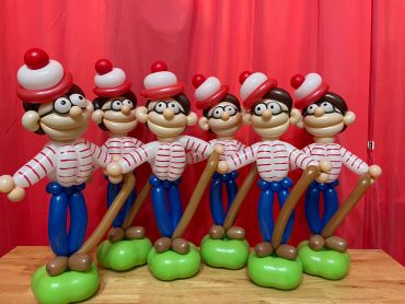 A row of six balloon sculptures resembling cartoon characters with hats and glasses.