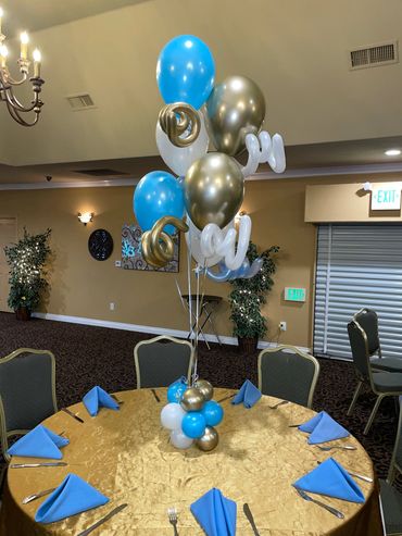 Elegant party table with blue and gold balloon centerpiece and blue napkins.