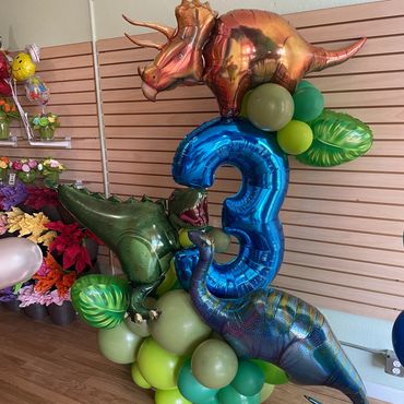Colorful dinosaur and number 3 balloons with greenery decorations.