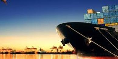 Cargo ship docked at port during sunset with containers stacked.