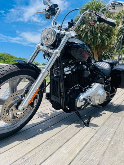 Shiny black cruiser motorcycle parked on wooden deck under blue sky.