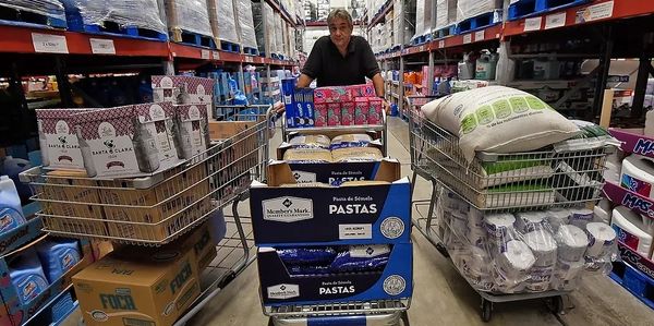 Todd Essick founder Caring Divers pushing shopping carts filled with bulk groceries in a warehouse store.