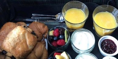 Breakfast tray with pastries, fruit, juice, and condiments.