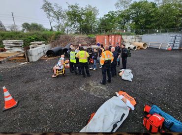 Emergency responders attending to a person on a stretcher in an outdoor area.