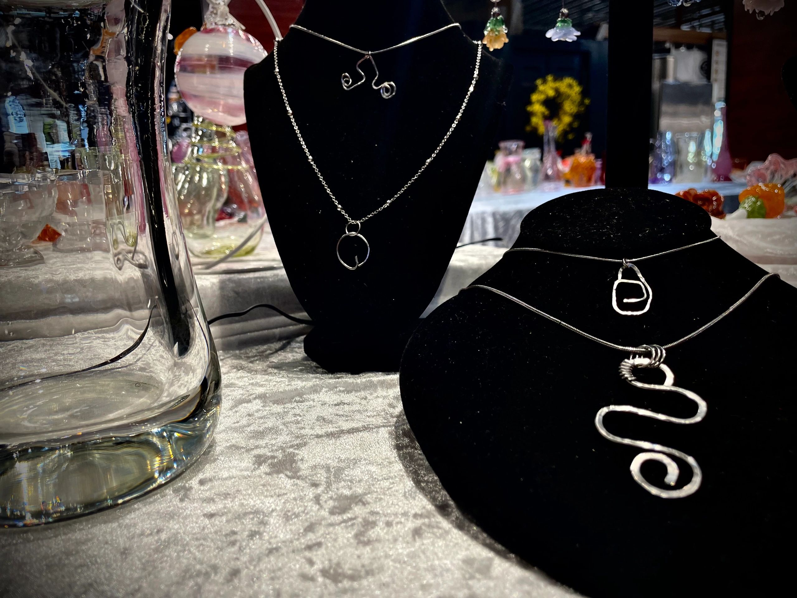 Handcrafted silver jewelry displayed on black velvet stands.
