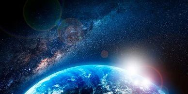Earth illuminated by the sun against a starry galaxy backdrop.