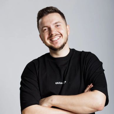 Lächelnder Mann mit schwarzem T-Shirt vor grauem Hintergrund.