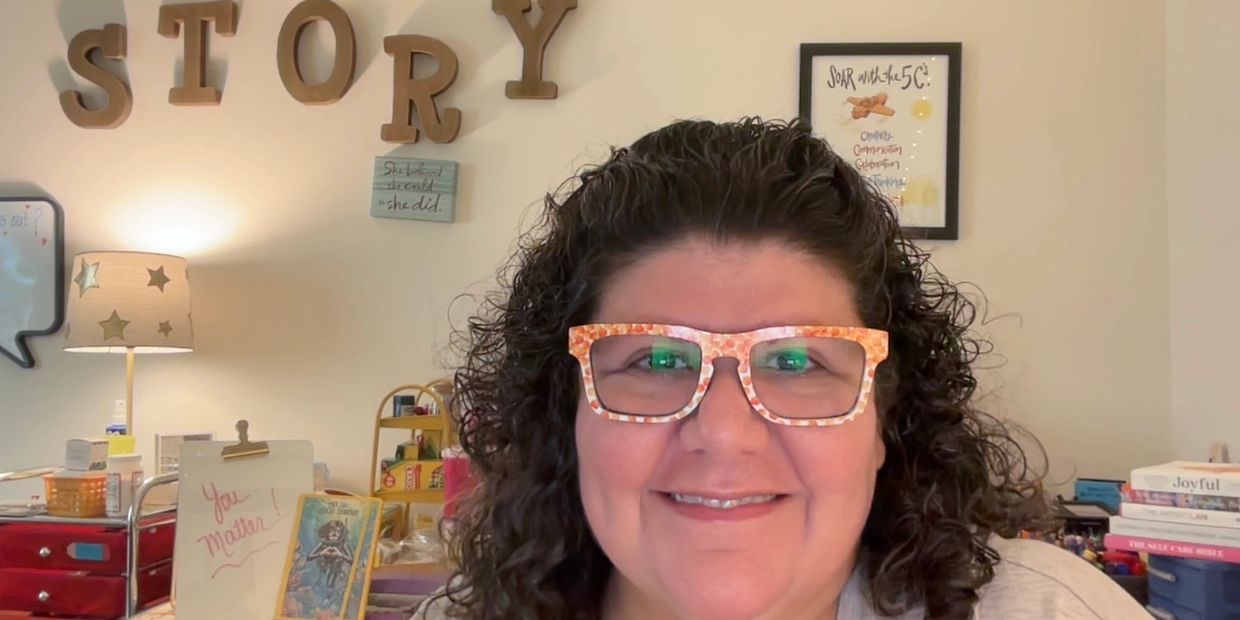 Photo of Michelle Haseltine with the word STORY  handing on the wall behind her. 