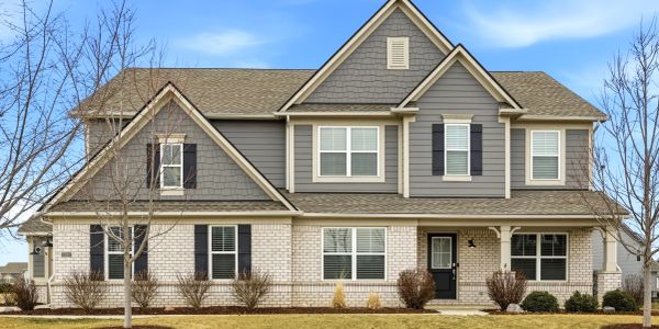 Two-story suburban house with gray siding and brick facade.