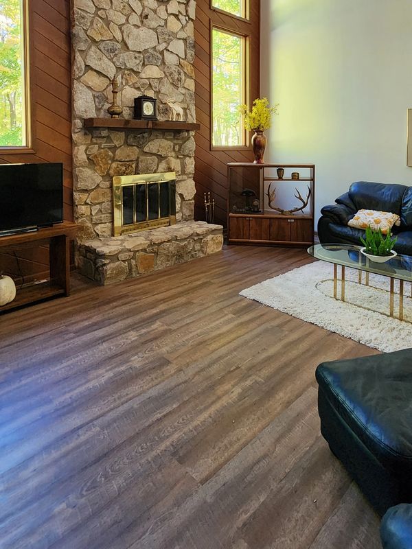 Cozy living room with stone fireplace and wooden floor.