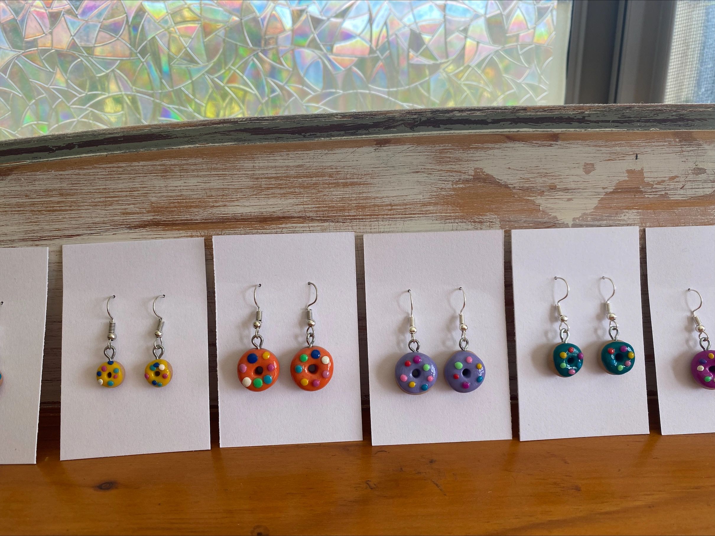 Picture of small colourful doughnut earrings displayed on white card stock.