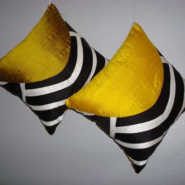 Two decorative cushions with yellow, black, and white geometric patterns.