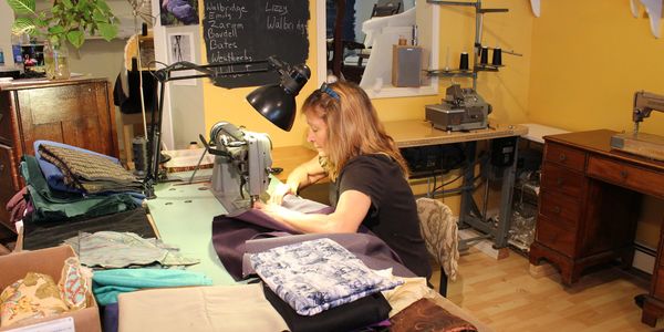 A woman sewing fabric using a sewing machine in a cozy workshop.