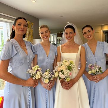 Bride with bridesmaids in light blue dresses holding bouquets.