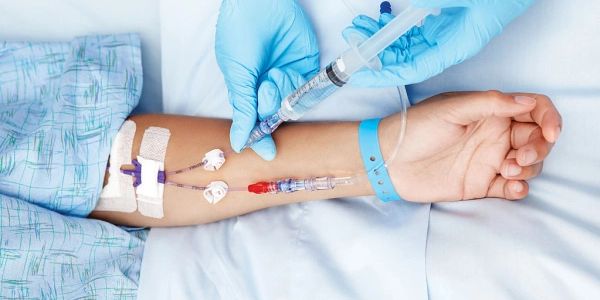 Medical syringe injection into patient's arm with IV line.