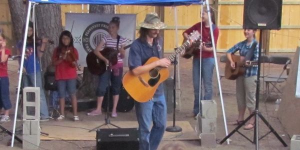 Group performing music outdoors under a canopy.
