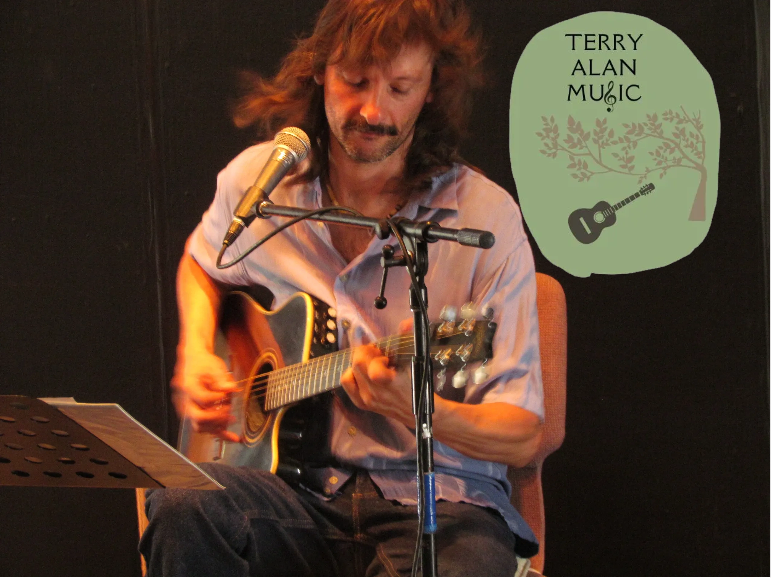 Musician playing guitar with a microphone and music stand.