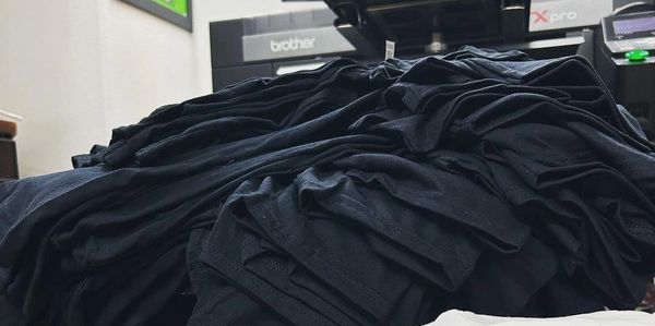Stacks of black and white folded t-shirts on a chair.