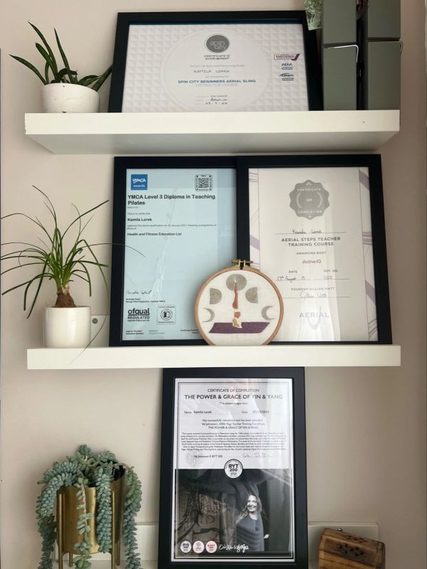 Three framed certificates with plants on white shelves.