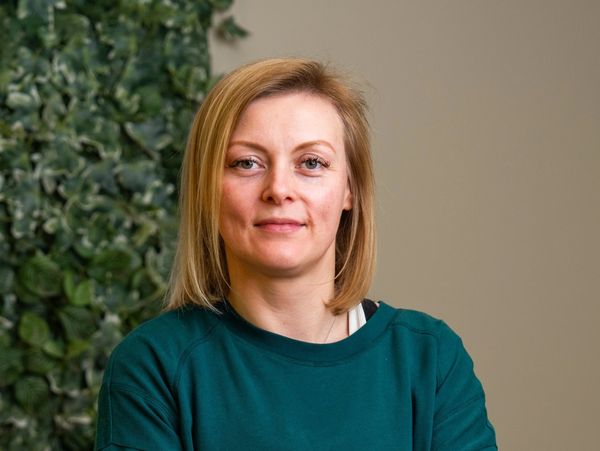 Woman in green top with neutral expression.
