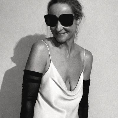 Woman in elegant satin dress and large sunglasses posing with confidence.