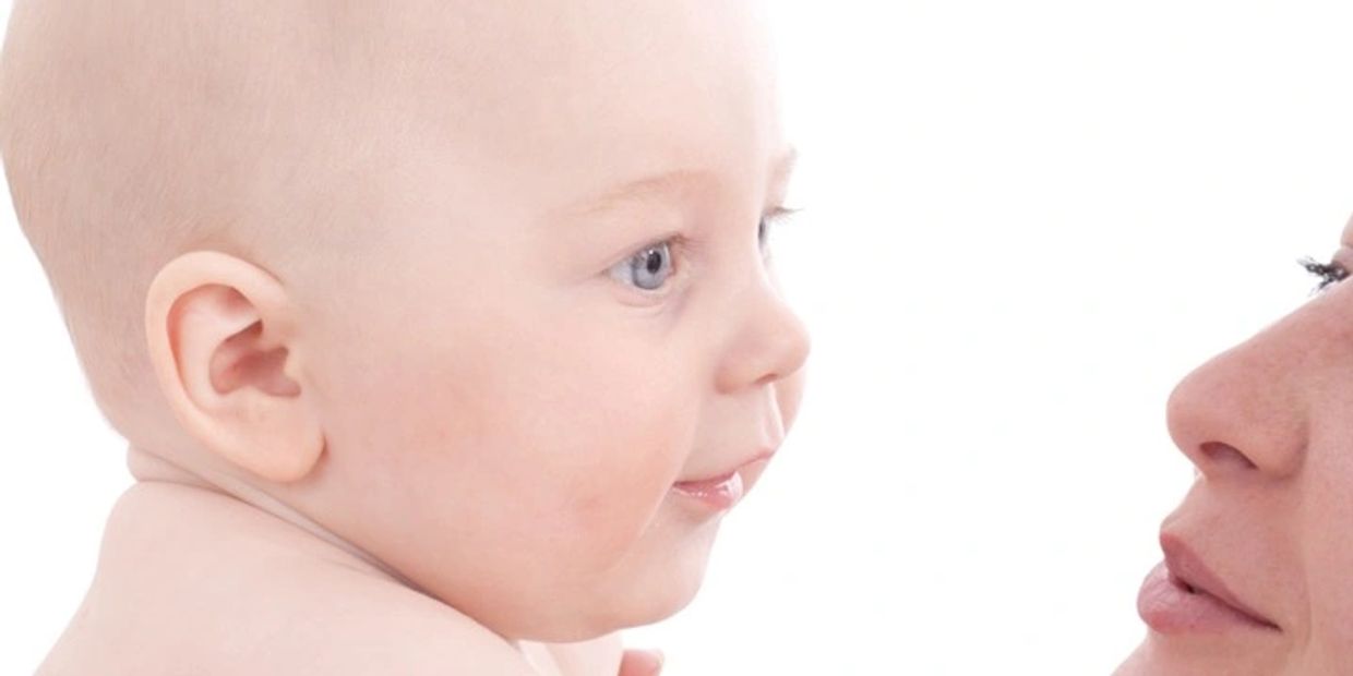 A mother holding and moving to kiss her baby