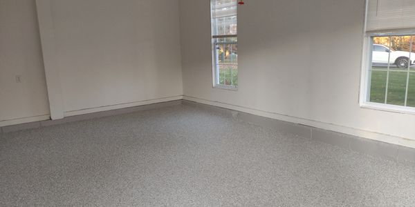 New garage epoxy floor with flakes before wall mounted cabinetry installation .
