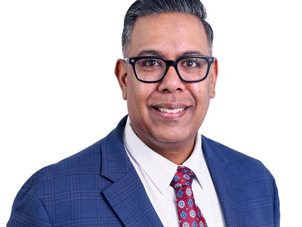 Professional man wearing glasses and a blue suit with a red patterned tie.