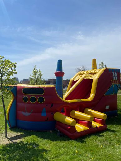 Inflatable pirate ship bounce house under a sunny blue sky.