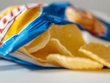Close-up of a blue Lay's potato chips bag with chips spilling out.