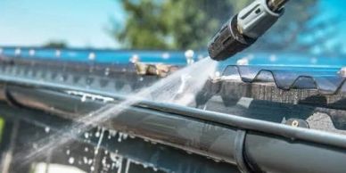 Cleaning gutters using a high-pressure water spray.
