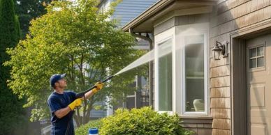 Man pressure washing house exterior.