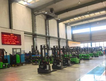 Warehouse with rows of green forklifts and equipment.