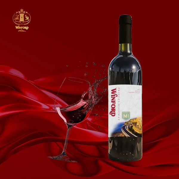 Winford wine bottle with a splash of red wine in a glass against a rich red backdrop.