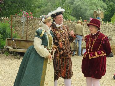 Three people in Renaissance-style costumes talking outdoors.
