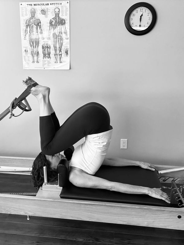Person doing Pilates exercise on a reformer machine.